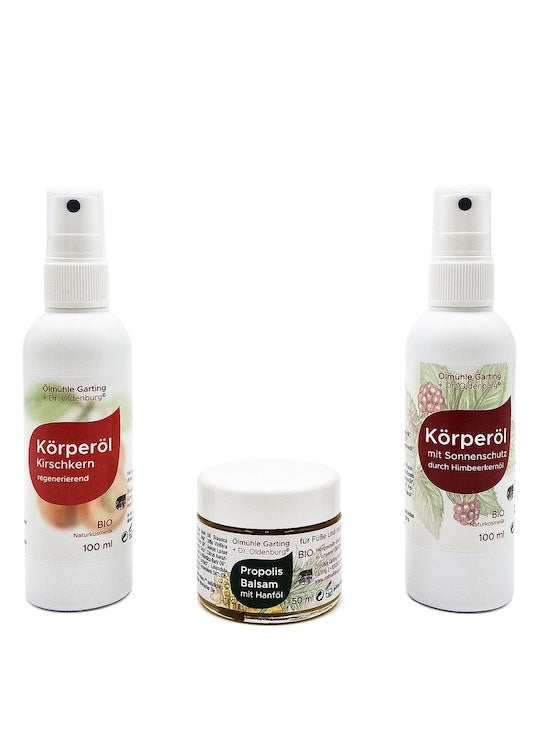Drei Naturkosmetik Körperpflegeprodukte der Ölmühle Garting: zwei Körperöle mit Kirschkern- und Himbeersamenöl sowie ein Propolisbalsam mit Hanföl in der Mitte