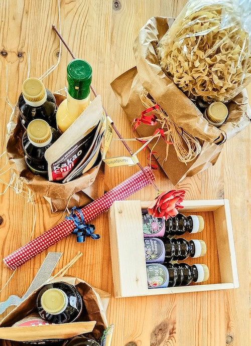 Geschenk- und Probiersets der Ölmühle Garting: liebevoll arrangierte Bio-Speiseöle, Nudeln und Feinkost in Holzboxen und Papiertüten auf Holztisch