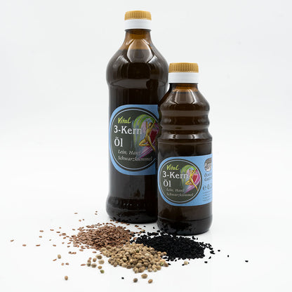 Vitalöl Set, 3 Kern Öl aus Lein, Hanf und Schwarzkümmelöl nativ kaltgepresst, 250 ml in brauner Glasflasche der Ölmühle Garting mit blauem Etikett auf weißem Hintergrund, im Vordergrund Leinsamen, Schwarzkümmelsamen und Hanfsamen