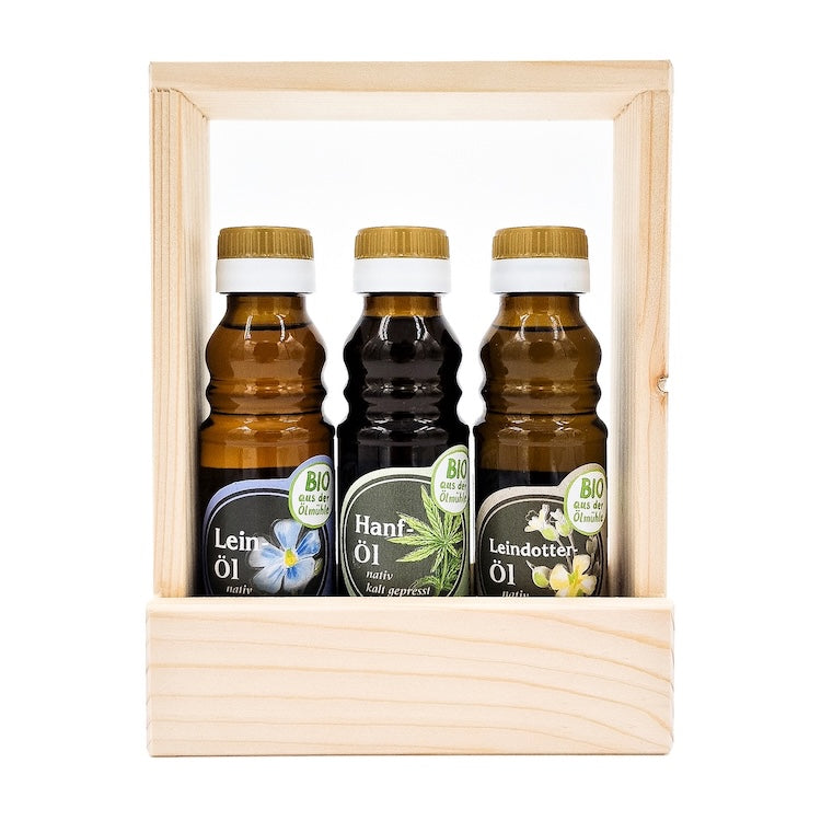 Geschenkset Bio Gesundheit kaltgepresst nativ mit 100 ml Flasche Bio Leinöl, 100 ml Flasche Bio Hanföl und 100 ml Bio Leindotteröl in einem Holztragerl auf weißem Hintergrund