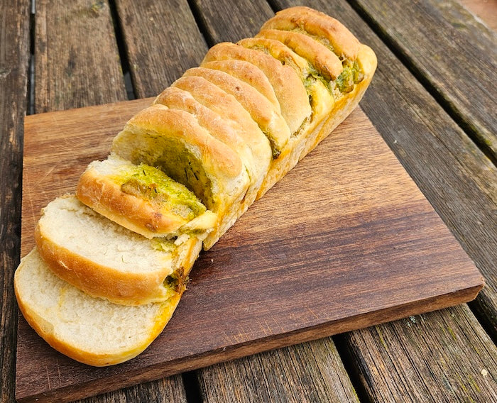 Faltenbrot mit Grillöl für Grillabende auf Holzbrett, im Hintergrund Holztisch