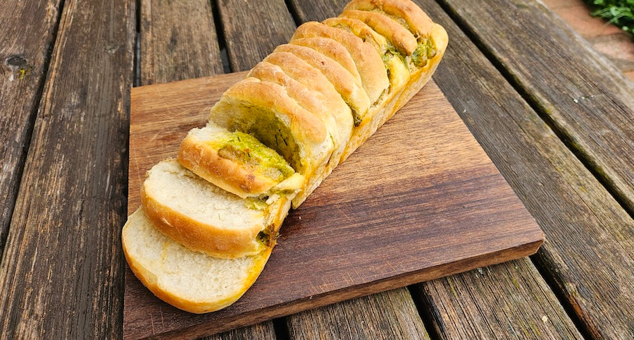 Faltenbrot mit Grillöl für Grillabende auf Holzbrett, im Hintergrund Holztisch