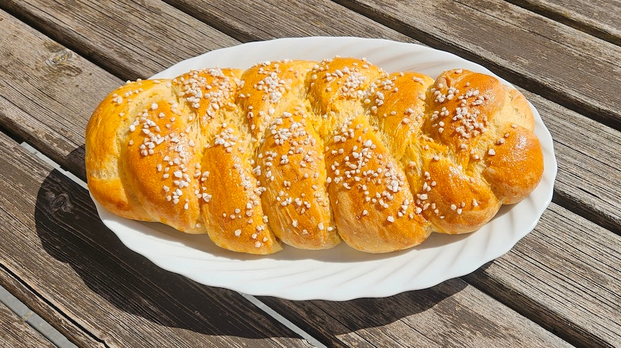 Hefezopf mit Kirschkernöl auf weißem Teller, im Hintergrund Holztisch