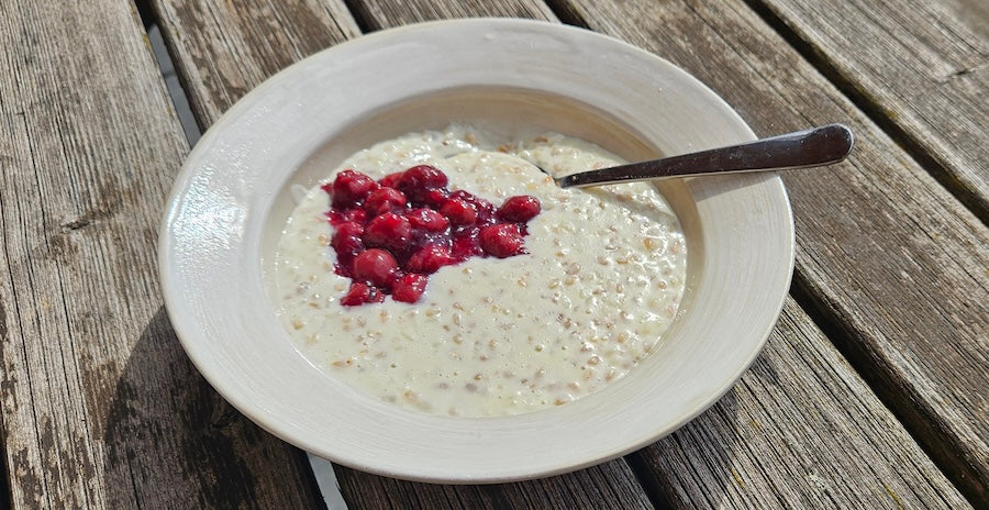 Milchreis mit Kirschen und Kirschkernöl in einem Suppenteller auf Holztisch