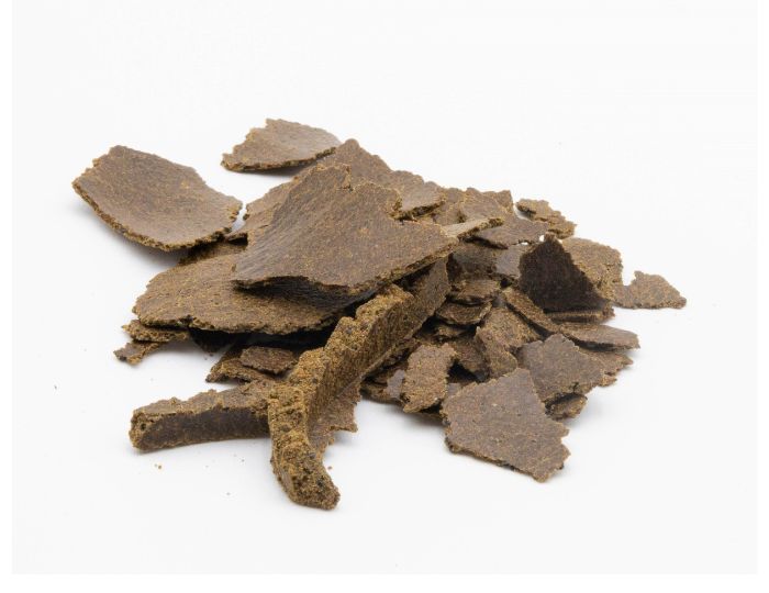 Leindotterkuchen Flakes braun als Futtermittel für Tiere auf weißem Hintergrund