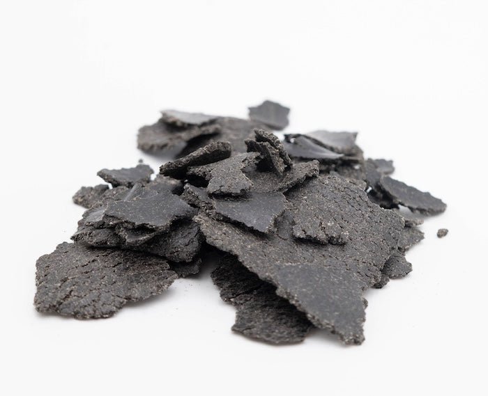 Schwarzkümmelkuchen Flakes als Futtermittel für Tiere auf weißem Hintergrund