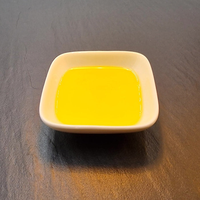 Goldgelbes Bio-High-Oleic-Sonnenblumenöl der Ölmühle Garting in einer weißen Schale auf dunkler Schieferfläche