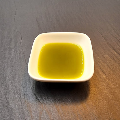 Bio Schnittlauch Petersilie Kräuteröl kaltgepresst nativ, grüngelbes Öl in weißer Schale vor grauem Hintergrund 